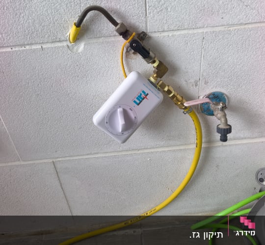 חיבור גז עם צינור צהוב על קיר לבן